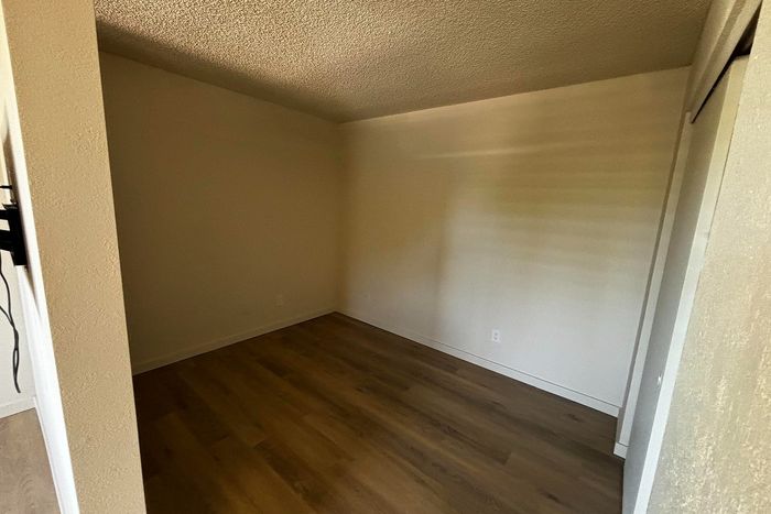 Cozy empty room with elegant hardwood flooring and textured ceiling, inviting personalization and creativity for a stylish living space.