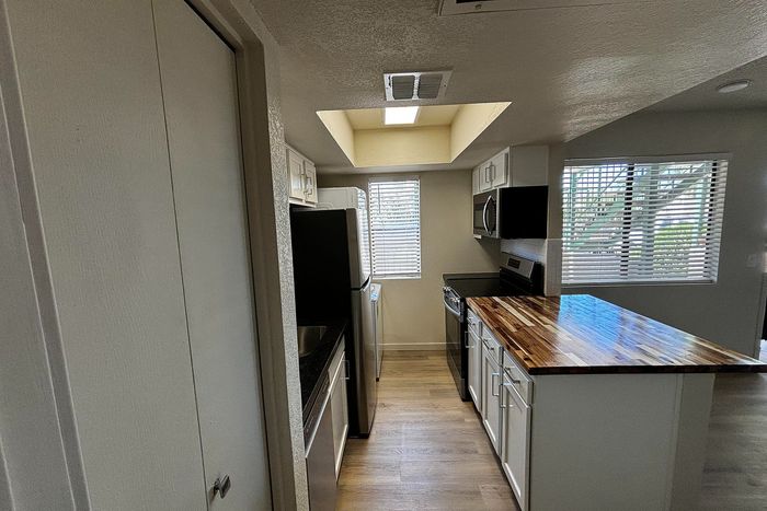 Chic modern kitchen with sleek cabinetry, stylish wooden countertops, and abundant natural light from large windows.