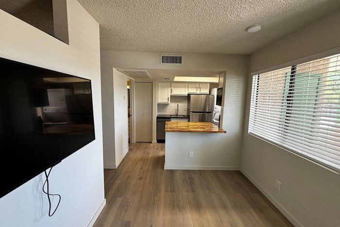 Modern apartment with sleek kitchen, stylish countertops, and spacious living area with large windows and a wall-mounted TV.