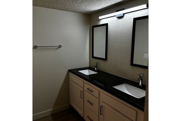 Sleek bathroom with modern dual sinks, elegant mirrors, and polished granite countertop.