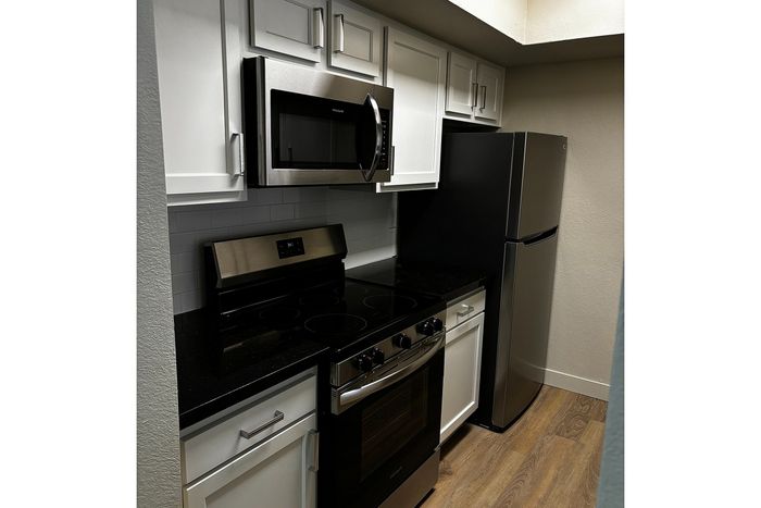 Modern kitchen with sleek stainless steel appliances, elegant white cabinetry, and a sophisticated black countertop.