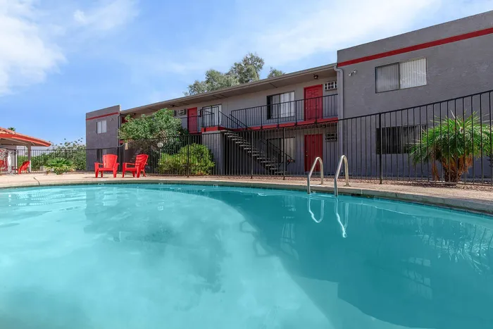 Inviting apartment complex with a refreshing outdoor pool, surrounded by lush greenery and modern architecture.