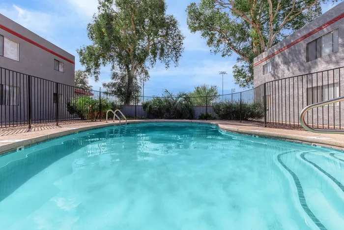 Inviting turquoise pool surrounded by lush greenery and modern apartment buildings, perfect for relaxation and leisure.