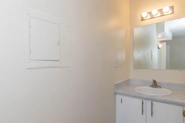 Bright and modern bathroom featuring a sleek countertop, stylish lighting, and a large mirror for a refined look.