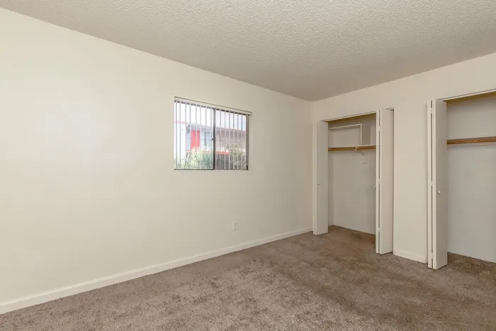 Bright and airy bedroom with soft carpet, ample closet space, and a window providing natural light, perfect for a cozy retreat.
