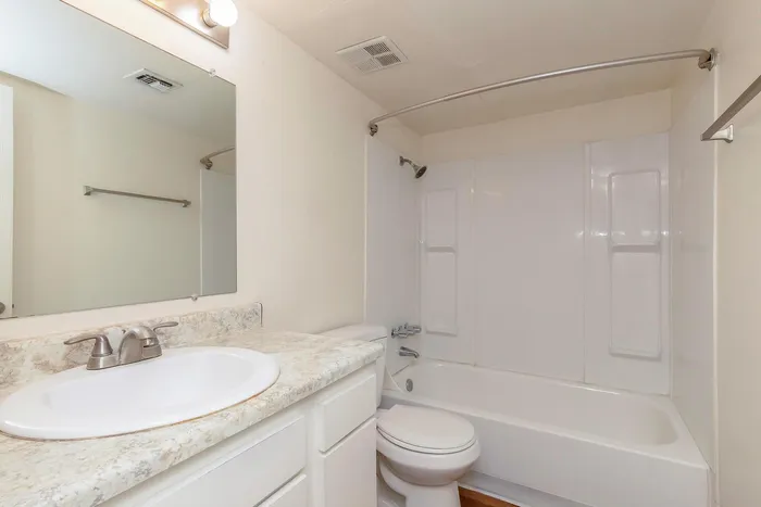 Bright and modern bathroom featuring a marble countertop, sleek fixtures, and a pristine bathtub.