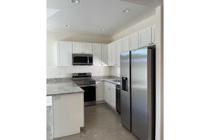 Modern kitchen with sleek stainless steel appliances, granite countertops, and white cabinetry.