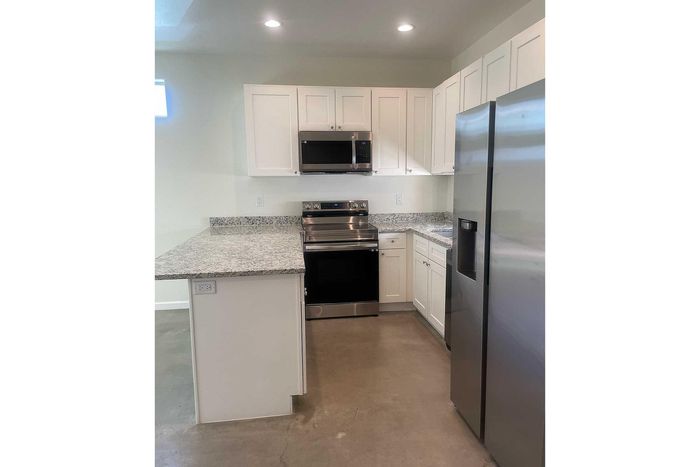 Modern kitchen with sleek stainless steel appliances, elegant granite countertops, and ample white cabinetry.