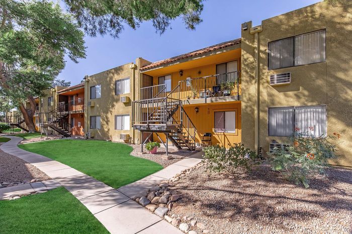Charming apartment complex with vibrant landscaping, mature trees, and inviting walkways for a serene living experience.