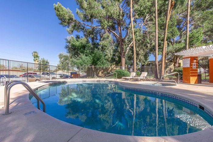 Serene outdoor pool area surrounded by lush greenery and tall trees, perfect for relaxation and leisure.
