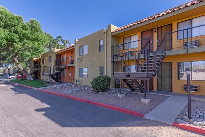 Charming apartment complex with vibrant exteriors, lush greenery, and ample parking space, perfect for convenient and comfortable living.
