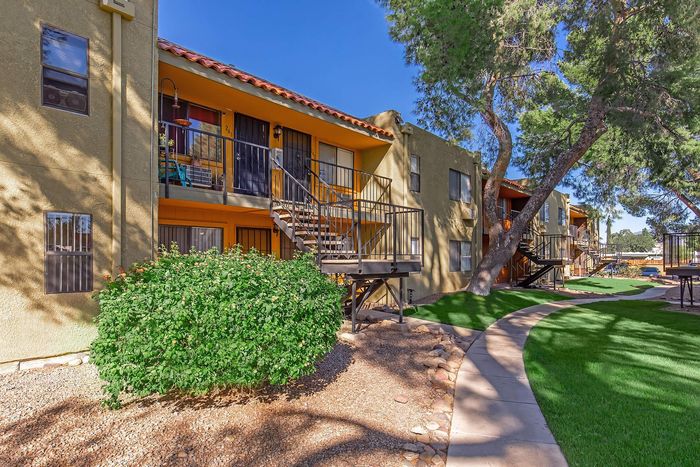 Charming apartment exterior with vibrant garden, offering shaded walkways and private balcony access.