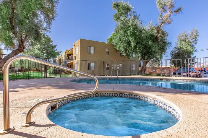 Inviting apartment complex with a sparkling pool and lush greenery, perfect for relaxation and leisure.
