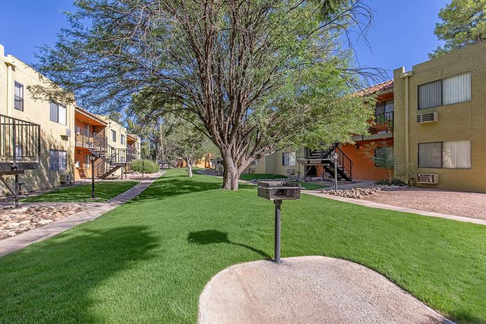 Charming apartment complex showcasing lush green lawns, mature trees, and inviting outdoor spaces for relaxation.