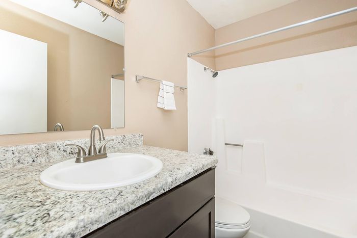 Contemporary bathroom featuring a sleek granite countertop, modern fixtures, and a clean, bright shower area.