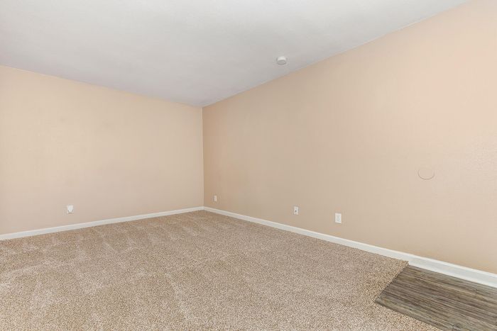 Bright, well-lit room with fresh beige carpeting and soft cream walls, offering a cozy and inviting atmosphere perfect for a bedroom or office space.