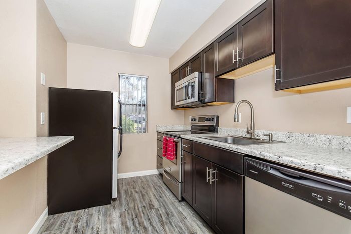 Contemporary kitchen boasting sleek dark cabinetry, stainless steel appliances, and elegant granite countertops.