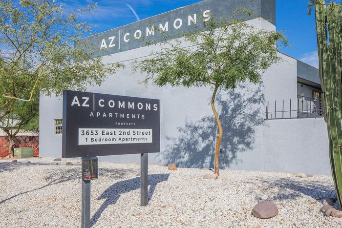 Modern AZ Commons Apartments entrance with contemporary architecture and lush trees, located at 3653 East 2nd Street, offering stylish 1-bedroom apartments.