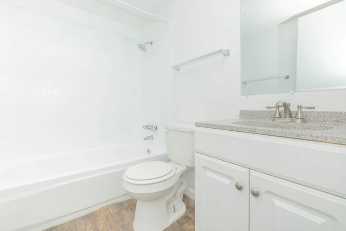 Bright and modern bathroom featuring sleek fixtures, a spacious bathtub, and elegant vanity with a granite countertop.