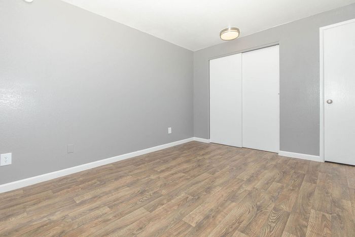Bright and spacious room featuring elegant hardwood flooring and sleek gray walls, offering a modern and inviting atmosphere.