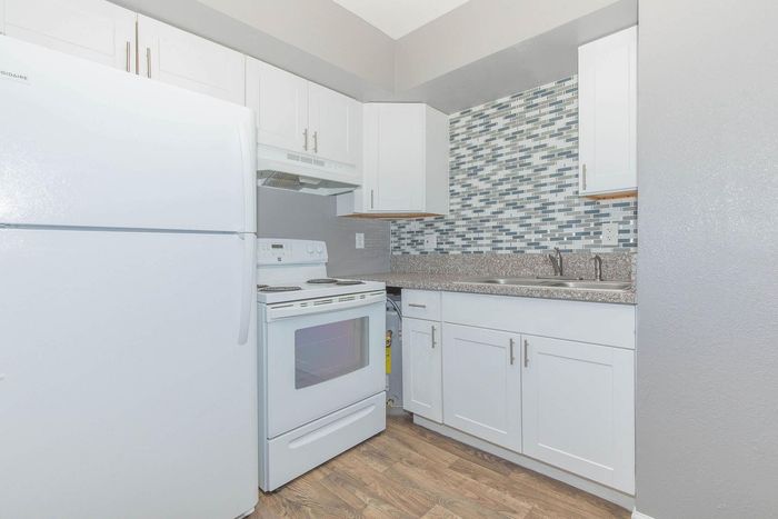 Contemporary kitchen with sleek white cabinetry, modern appliances, and stylish mosaic backsplash.