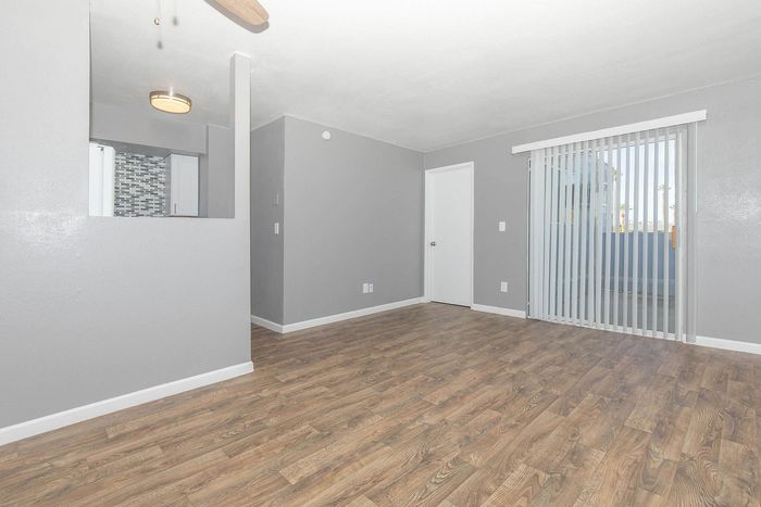Bright living space with elegant laminate flooring, contemporary lighting, and large sliding glass doors opening to a serene balcony.