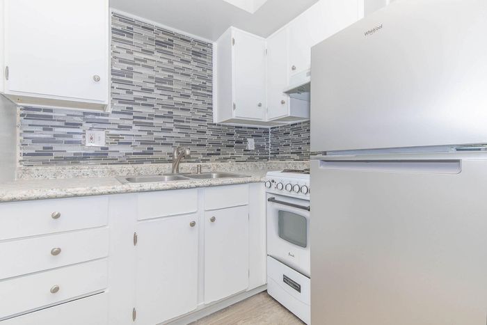 Contemporary kitchen with sleek stainless steel appliances, stylish mosaic backsplash, and elegant cabinetry.