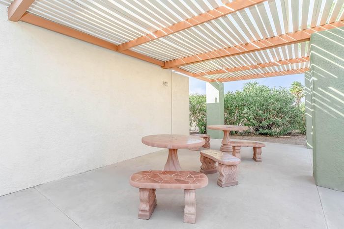 Charming outdoor pergola with stylish stone seating, perfect for relaxation and socializing in a serene garden setting.