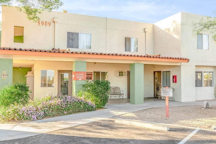 Bright and inviting apartment complex exterior showcasing a welcoming leasing office with lush landscaping, ideal for prospective residents.
