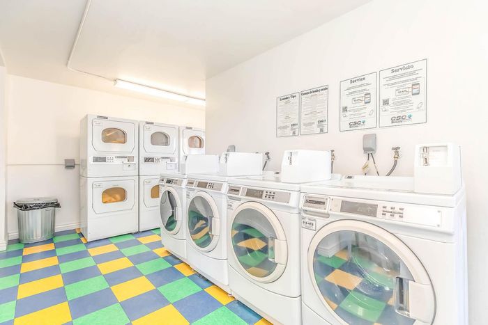 Bright and clean apartment laundry room with modern washing machines and colorful tiled flooring.