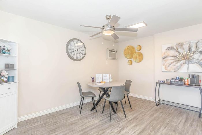 Charming dining area with contemporary gray chairs around a round table, stylish wall clock, elegant decor, and a cozy coffee bar setup.