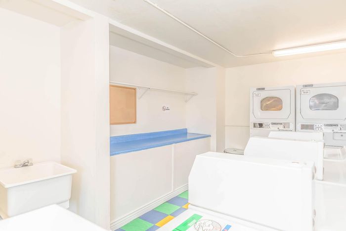 Bright and inviting communal laundry room featuring modern washing machines, colorful flooring, and ample folding space.