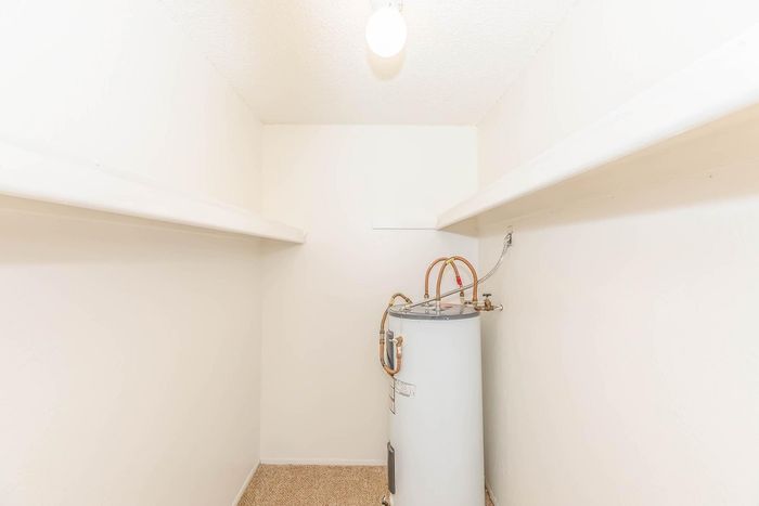 Bright utility room with ample shelving and modern water heater, perfect for organized storage solutions.
