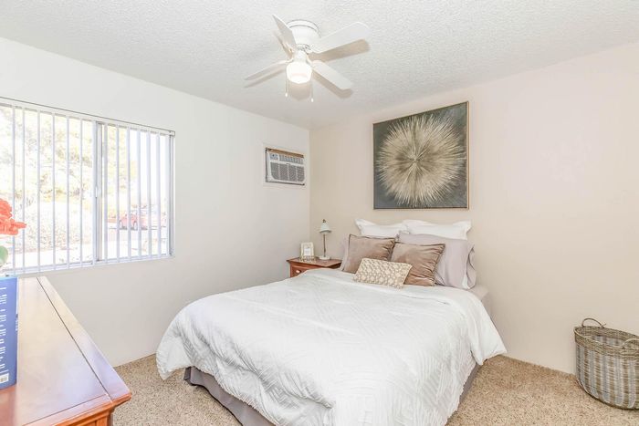 Bright and airy bedroom with modern decor, featuring a comfortable bed, elegant artwork, and a ceiling fan for added comfort.