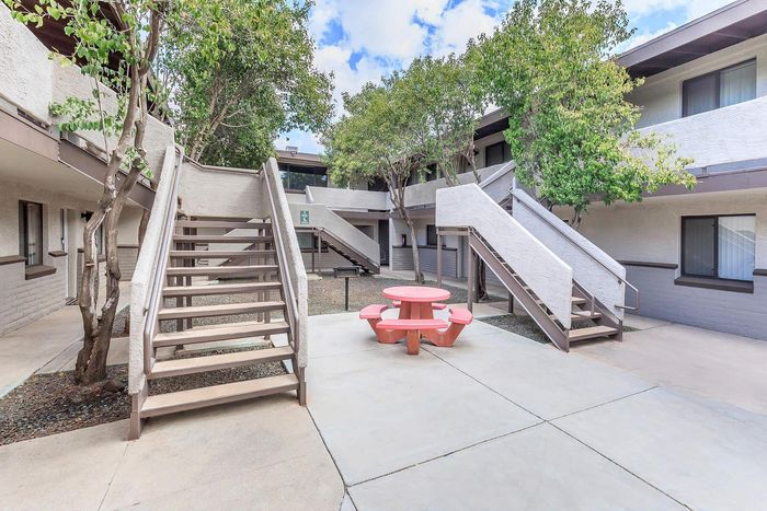 Inviting courtyard with modern staircases, lush greenery, and a charming red picnic table, perfect for outdoor relaxation.