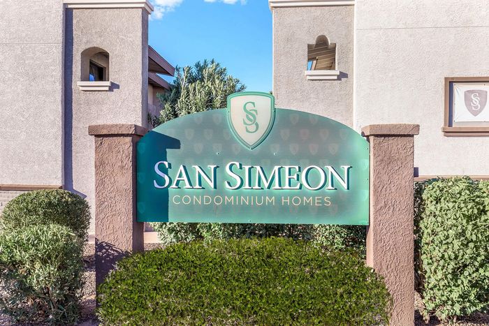 Inviting entrance sign of San Simeon Condominium Homes surrounded by lush greenery and elegant architecture.
