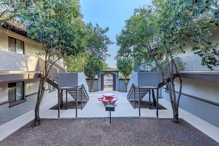 Charming apartment courtyard with lush trees, stylish staircases, and a cozy picnic area for relaxation.