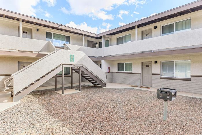 Charming apartment complex with a bright open courtyard, featuring modern exterior design and convenient outdoor stair access.
