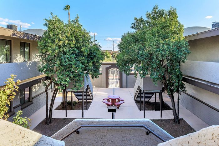 Charming apartment courtyard featuring lush greenery and a central picnic area, perfect for relaxation and community gatherings.