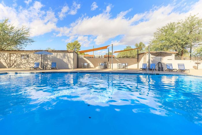 Inviting outdoor pool area with sun loungers and shaded seating under a clear blue sky, perfect for relaxation.