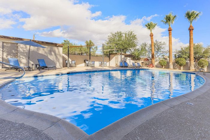 Inviting outdoor pool area with palm trees and lounge chairs, perfect for relaxation and sunshine.