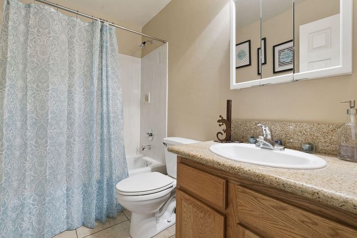Inviting bathroom with elegant tiled flooring, granite countertop, and stylish shower curtain in calming blue tones.