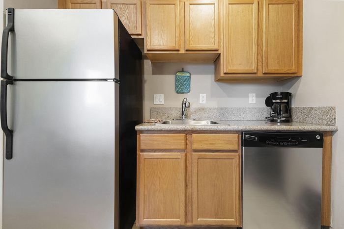 Modern kitchen design featuring stainless steel fridge, sleek countertops, and wooden cabinetry complemented by a stylish dishwasher.