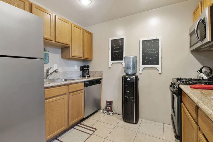 Modern kitchen with sleek stainless steel appliances, warm wooden cabinetry, and elegant granite countertops.