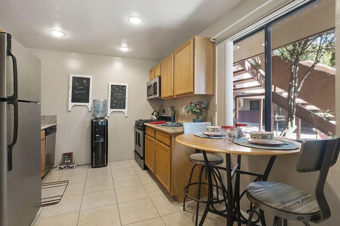 Charming kitchen interior with modern appliances, warm wooden cabinets, stylish bar seating, and bright natural light from large windows.