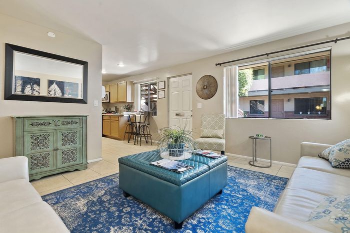 Bright and inviting living room with cozy sofas, elegant decor, and a modern open-concept kitchen area.