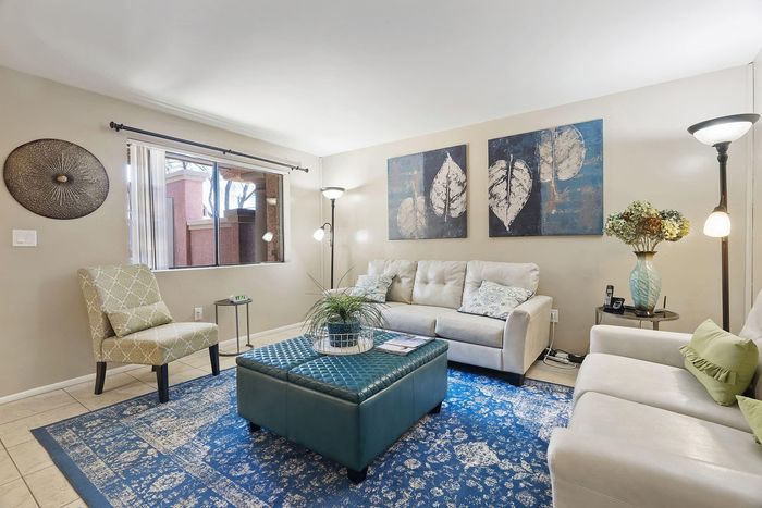 Elegant living room with chic decor, featuring a plush white sofa, stylish artwork on the wall, and vibrant blue accents.