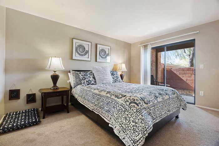 Inviting bedroom with elegant decor featuring a comfortable bed, stylish bedding, bedside lamps, and natural light from the sliding glass door leading to a cozy patio.
