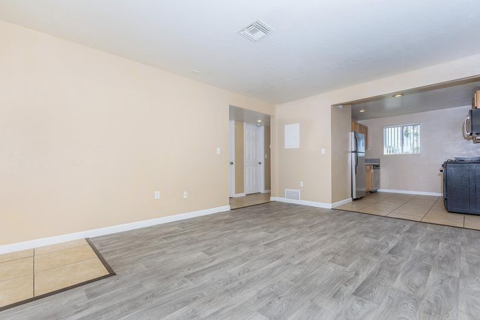 Bright open-plan apartment with sleek wooden flooring and a modern kitchen featuring stainless steel appliances.