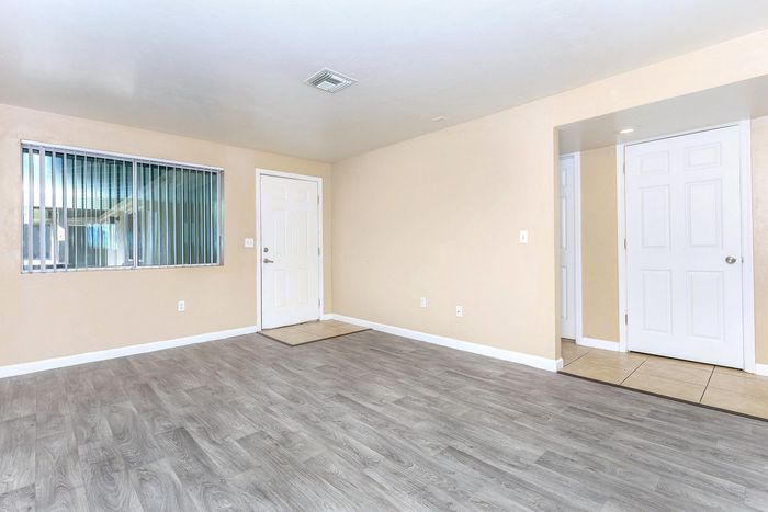 Bright and inviting living room with modern light gray flooring and natural light through large windows.